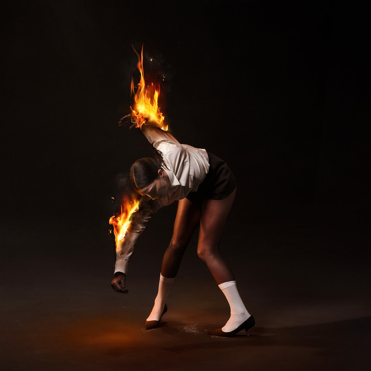 The cover of "All Born Screaming": a photo of Annie Clark hunched over and on fire